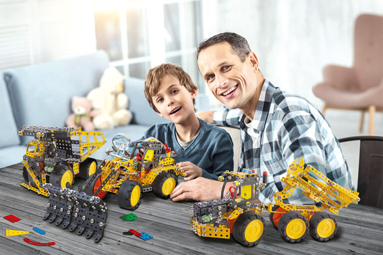 Smiling boy holding compasses and sitting with his daddy